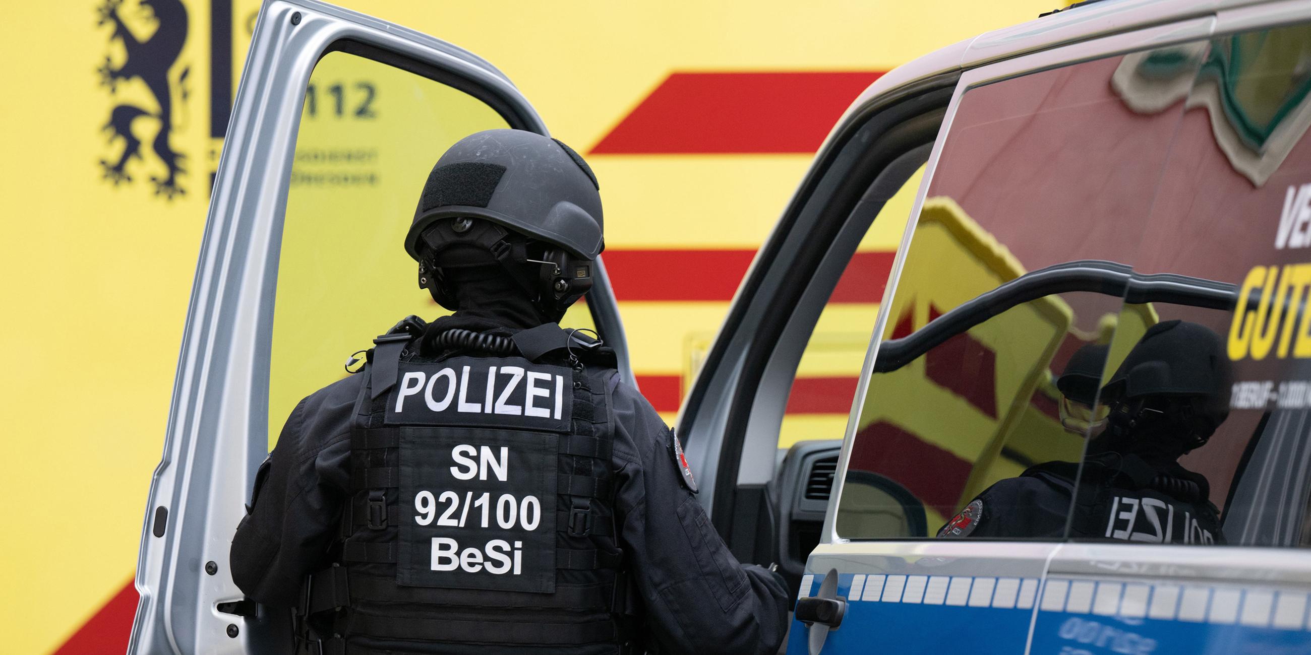 Eine Polizistin steigt im Dresdner Stadtteil Leipziger Vorstadt auf der Rudolf-Leonhard-Straße vor einem Krankenwagen in ein Polizeiauto.