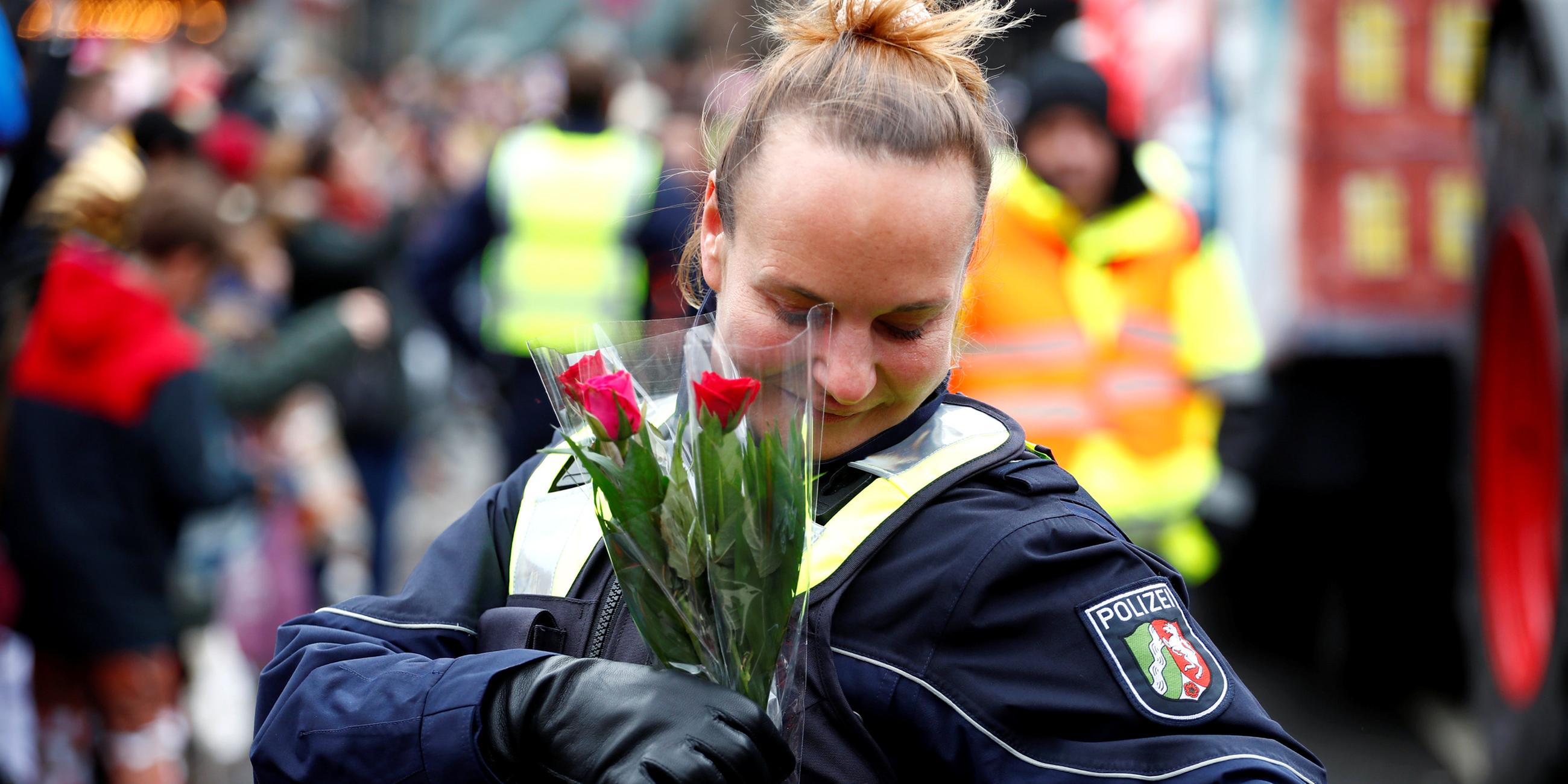 Eine Polizistin steckt sich am Düsseldorfer Rosenmontagszug ein paar Blumen in die Jacke