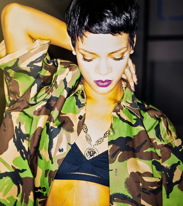 Rihanna mit kurzen Haaren und in einer tarnfarbenen Jacke steht in Pose und blickt runter auf den Boden.