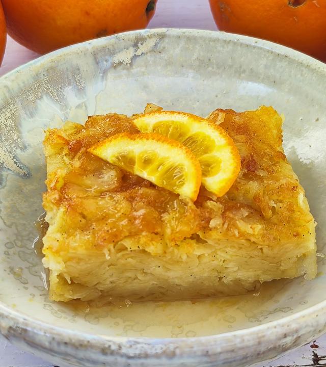 Tiefer Teller mit dem griechischen Orangenkuchen "Portokalópita", getoppt mit zwei Stücken einer Orange.