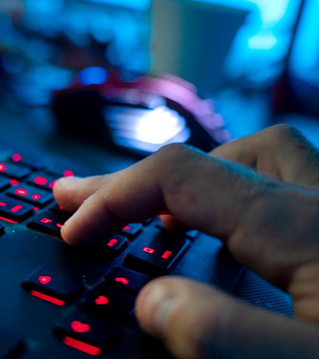 Ein Mann sitzt am Rechner und tippt auf einer Tastatur.