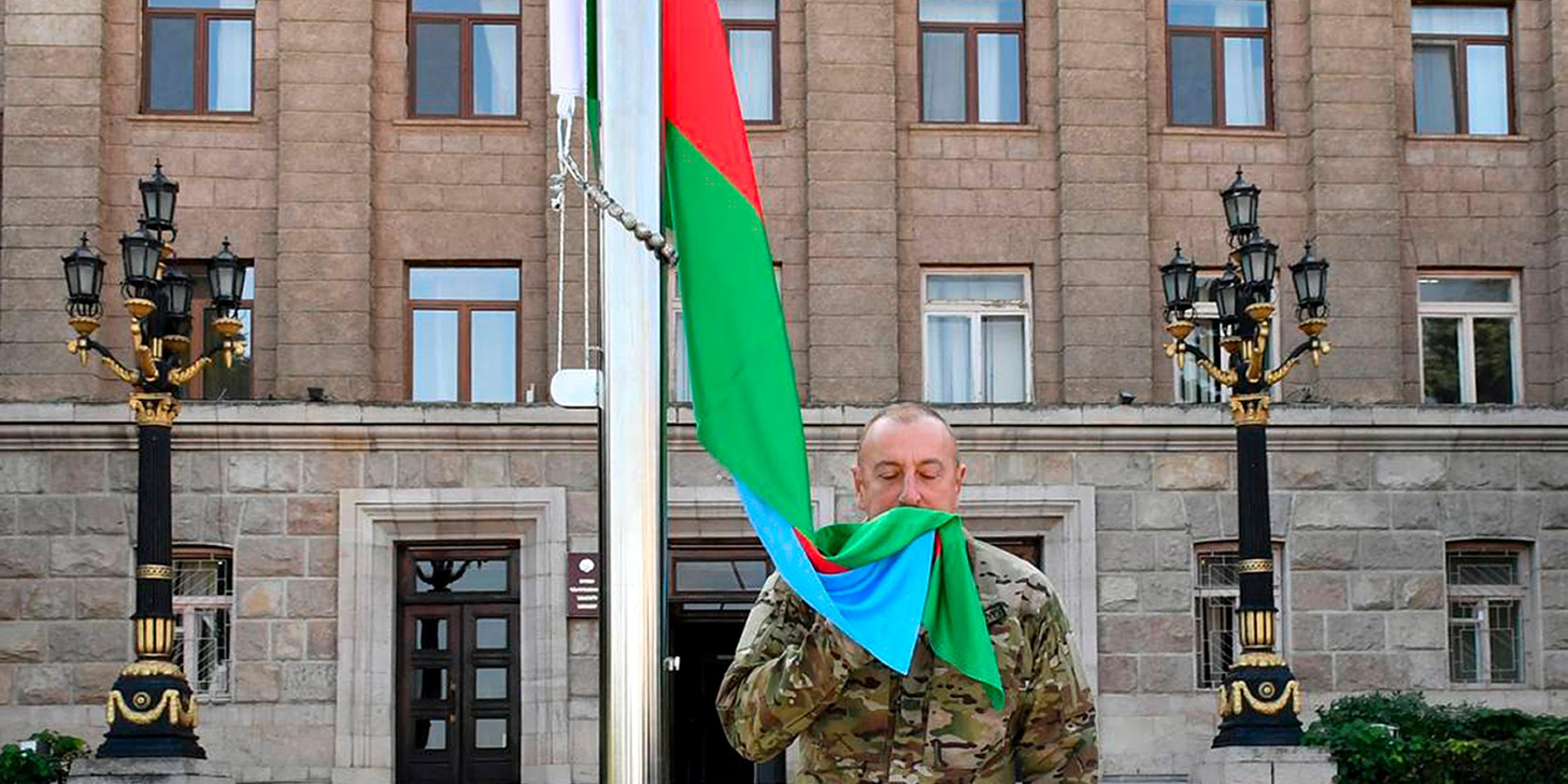 Aserbaidschans Präsident Ilham Aliyev hisst und küsst die aserbaidschanische Flagge in der Hauptstadt von Bergkarabach.
