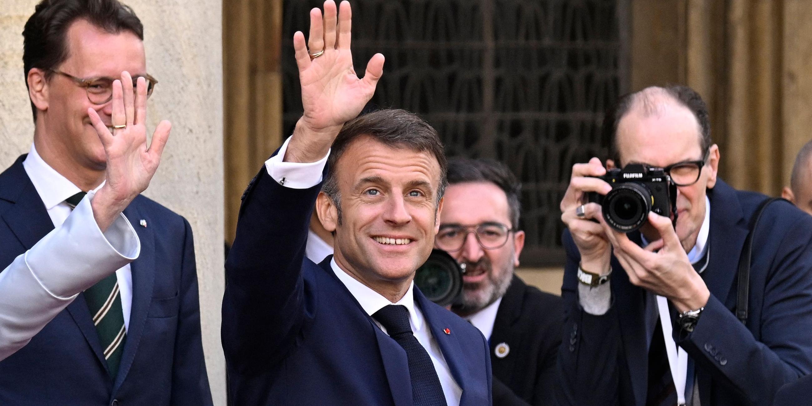 Der französische Präsident Emmanuel Macron (Mitte) winkt bei seiner Ankunft vor dem Rathaus in Münster, wo ihm am 28. Mai 2024 der Westfälische Friedenspreis verliehen wird.
