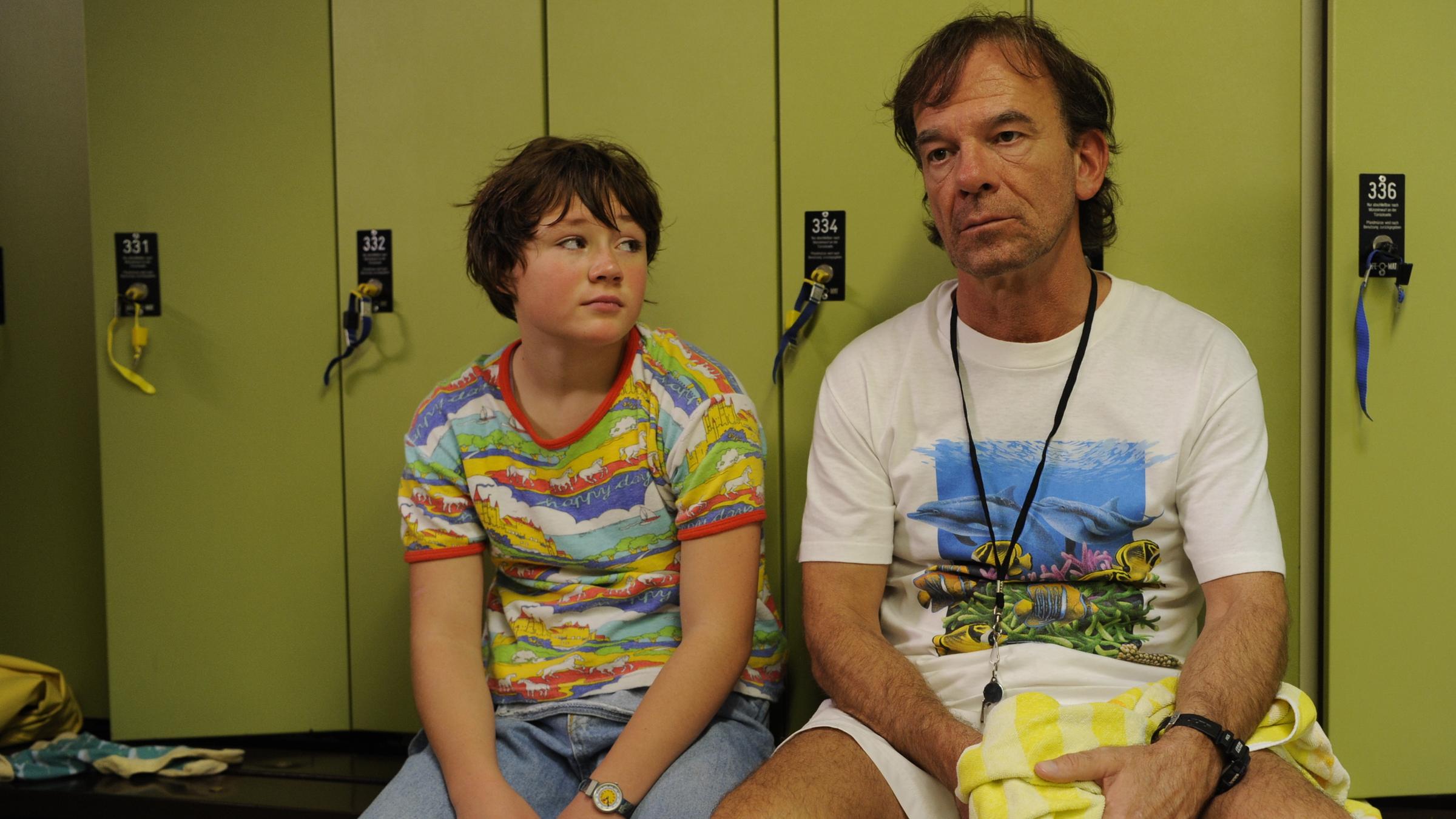 "Glück ist was für Weicheier": Jessica (Ella Frey) und ihr Vater Gabriel (Martin Wuttke) sitzen ratlos vor den Umkleideschränken im Schwimmbad.