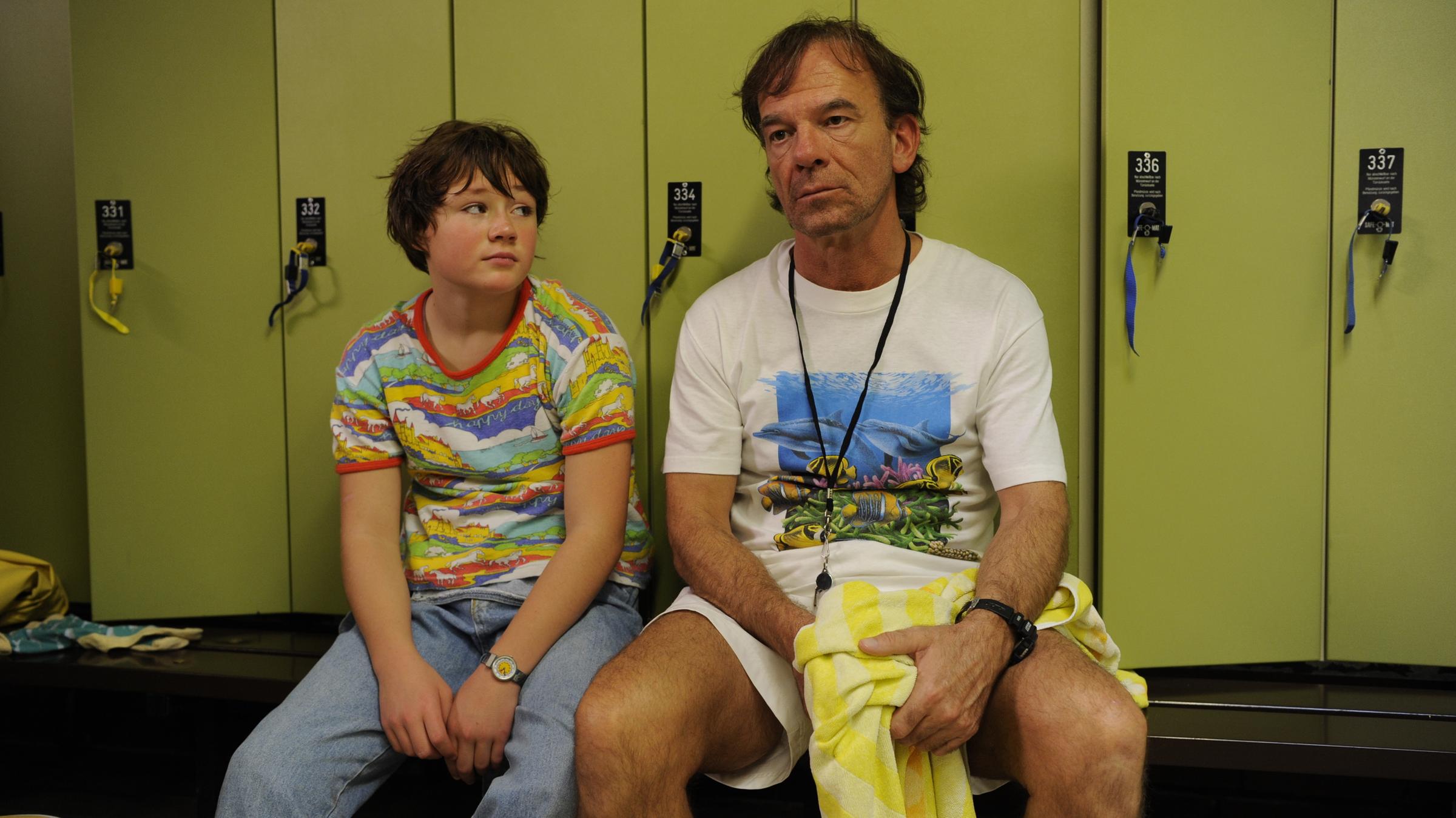 "Glück ist was für Weicheier": Jessica (Ella Frey) und ihr Vater Gabriel (Martin Wuttke) sitzen ratlos vor den Umkleideschränken im Schwimmbad.