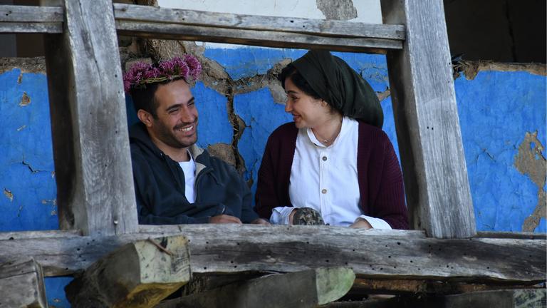 "Es gibt kein Böses": Der junge Soldat Javad (Mohammad Valizadegan) und seine Verlobte Nana (Mahtab Servati) stehen nebenewinander auf einem Balkon und lächeln sich an.