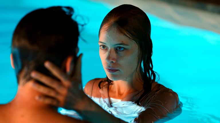 Undine (Paula Beer) und Christoph (Franz Rogowski)  stehen sich in einem Schwimmbecken gegenüber und blicken sich an. Undine hat ihre linke Hand auf seinen Hals und sein Gesicht gelegt.