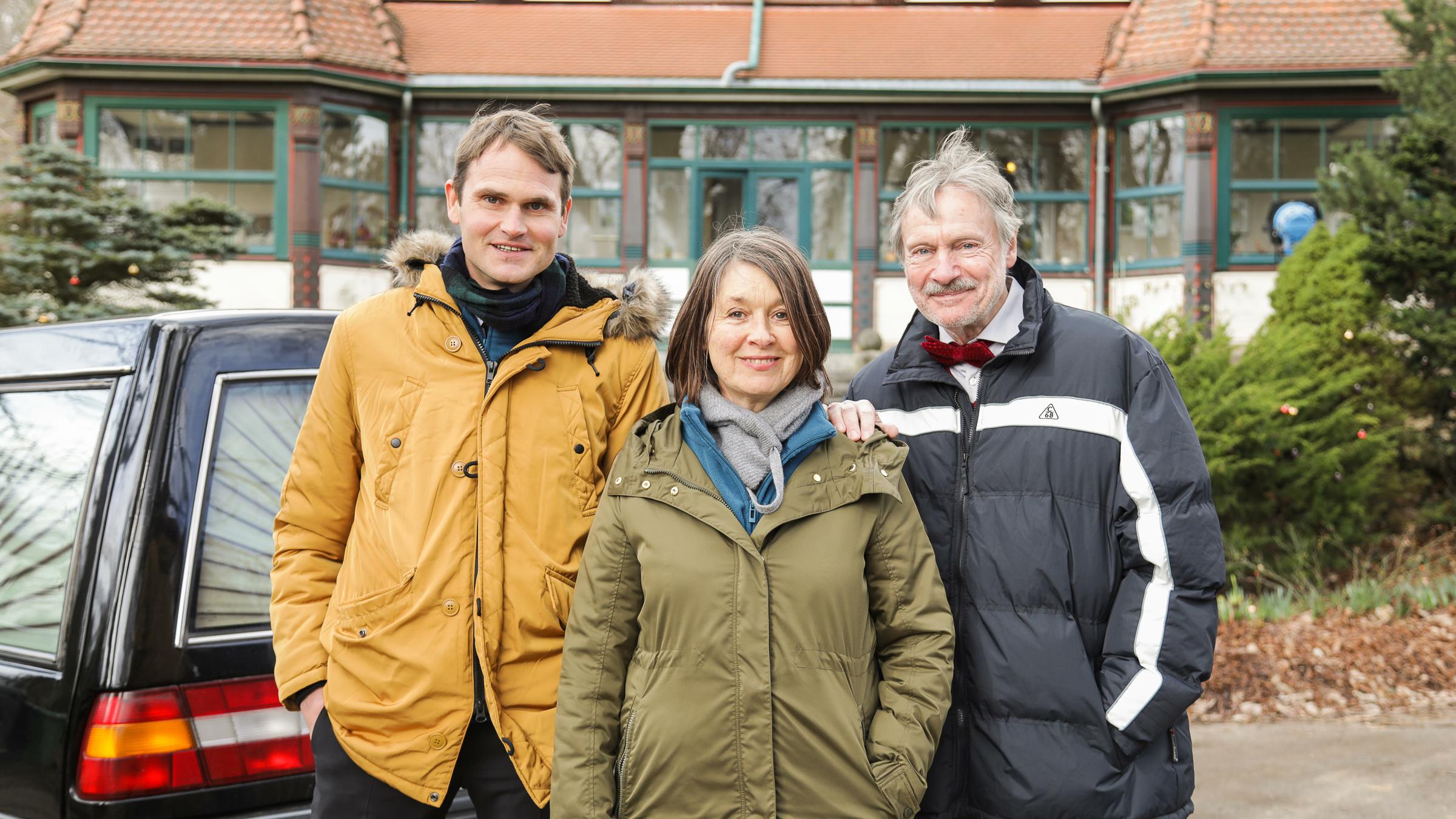 "Irgendwann ist auch mal gut": Die Hauptdarsteller Fabian Hinrichs,  Franziska Walser und Michael Wittenborn (v.l.n.r.) stehen vor einem Bestattungsfahrzeug.
