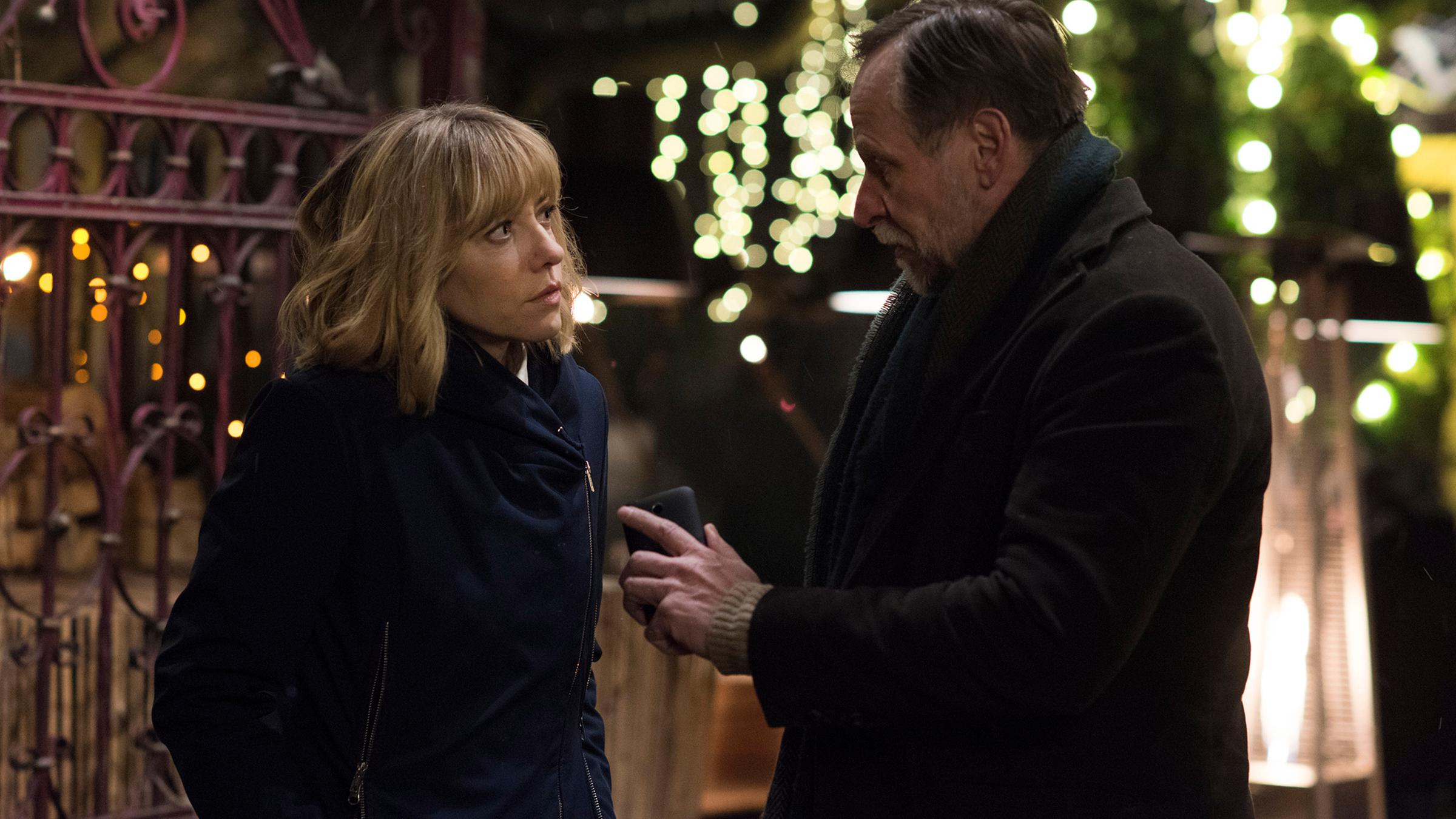 "Das Lustprinzip": Die Kommissare Victor (Karel Roden) und Maria (Malgorzata Buczkowska) stehen auf der nächtlichen Straße und unterhalten sich. Im Hintergrund ist ein schmiedeeisernes Tor zu sehen.