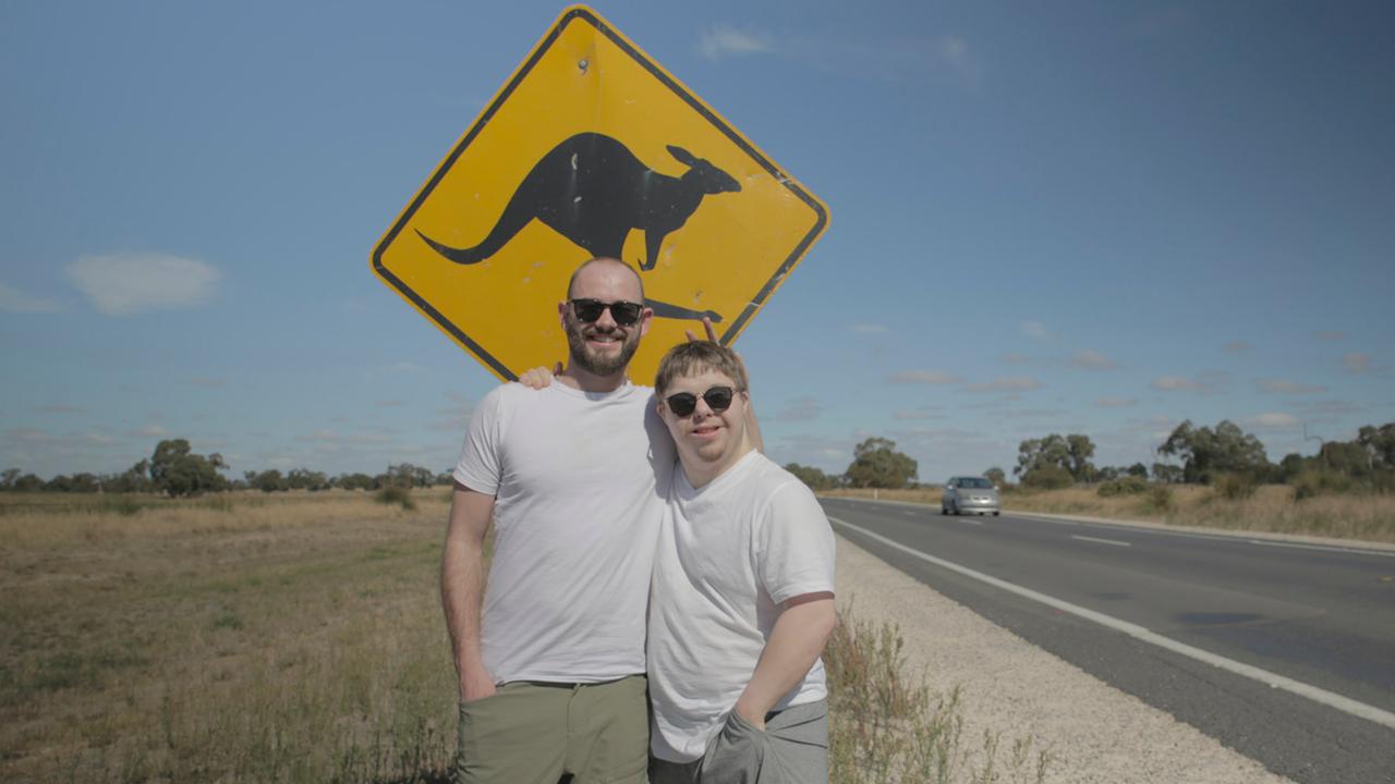 "Manuel Down Under" (ARTE): Julius Werner (l.) und Manuel Zube (r.) stehen Arm in Arm an einer australischen Landstraße vor einem typischen, gelben Känguruh-Warnschild.