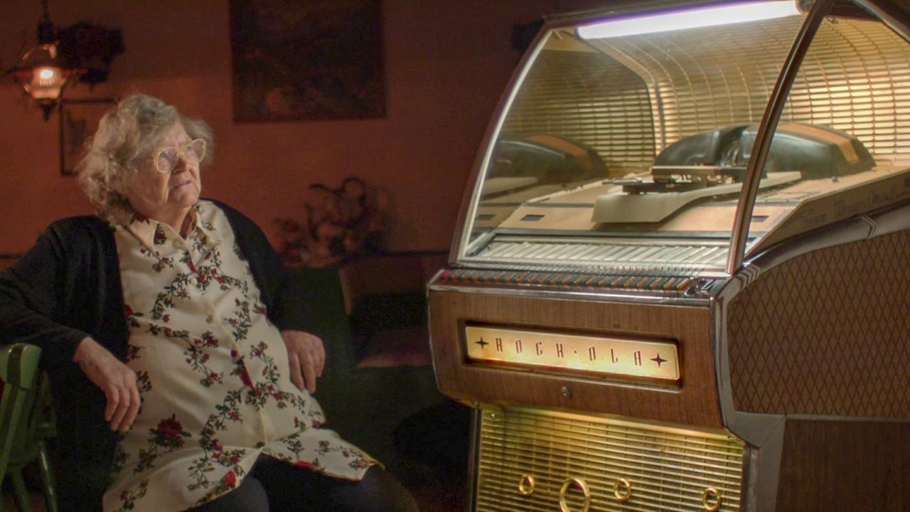 "80000 Schnitzel": Die 83-jährige Berta Zenefels sitzt in der Gaststube ihres Gast- und Bauernhofs neben einer alten Musicbox.