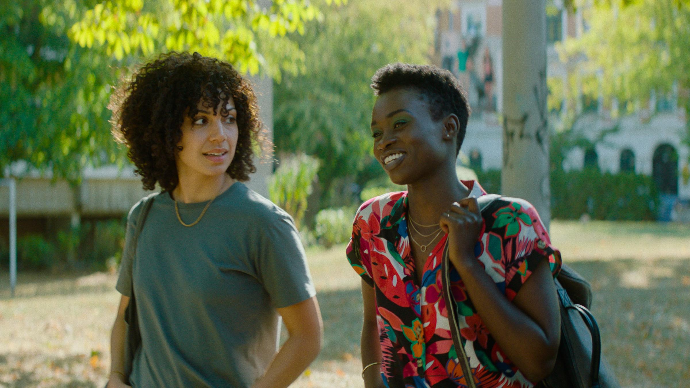 "Ivie wie Ivie": Ivie (Haley Louise Jones) und Naomi (Lorna Ishema) laufen durch einen Park, dabei blickt sie die lachende Naomi von der Seite an.