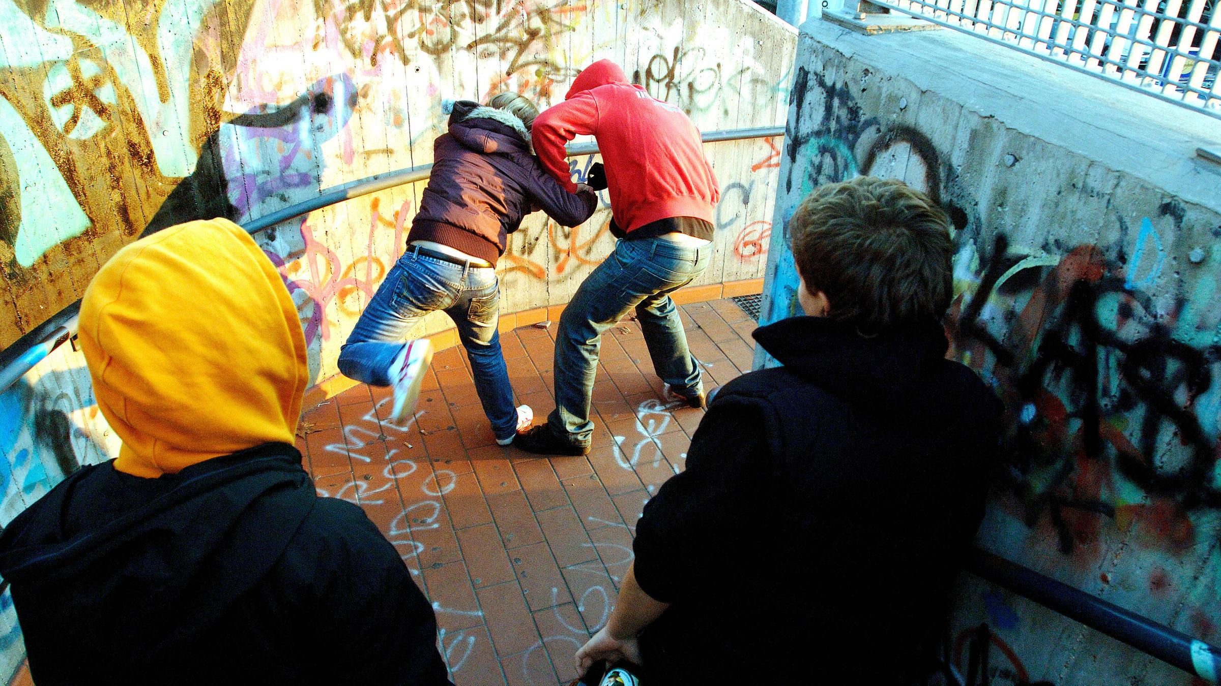 "Außer Kontrolle - Jugendgewalt in Deutschland": Zwei Jungen, einer mit roter und einer mit brauner Jacke, sind in eine Prügelei verwickelt. Beide tragen Kapuzen, ihre Gesichter sind nicht zu sehen. Zwei weitere Jugendliche schauen zu.