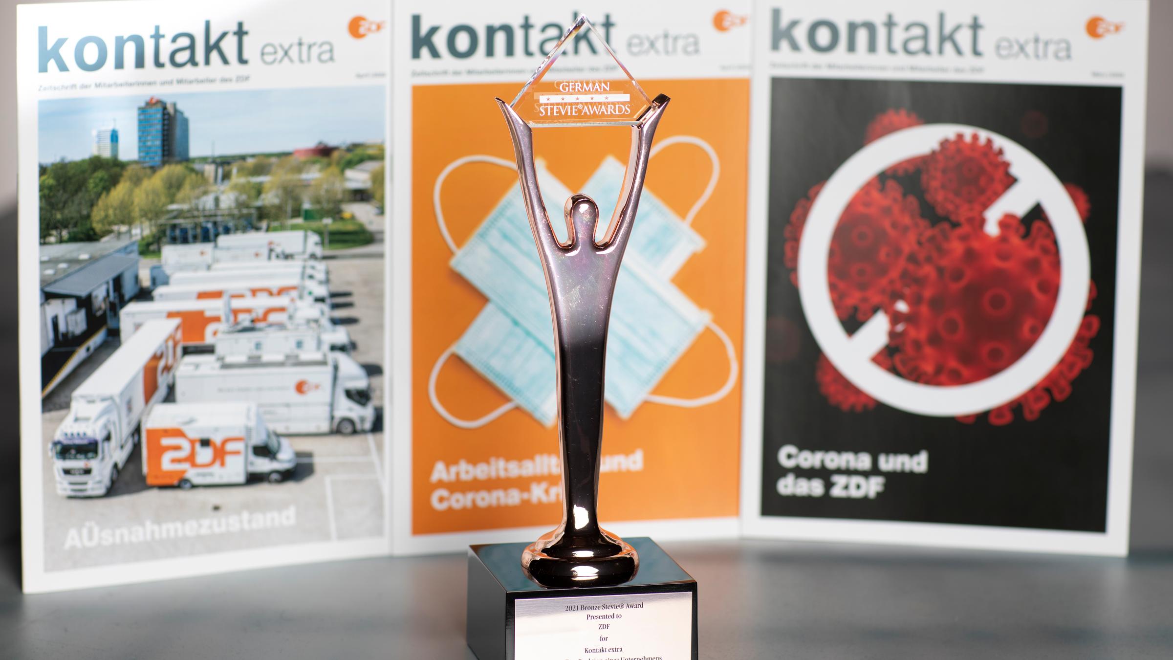 Die drei ausgezeichneten Corona-Sonderausgaben von "Kontakt" (in kleinster Auflage nachdgedruckt); davor die Preistrophäe