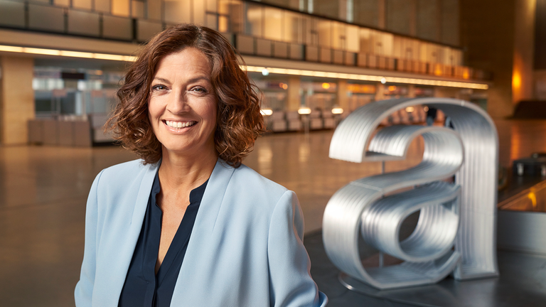 Kampagne "das Design der ZDF-Magazin" (Stilll): In einer großen Halle inks Antje Piper, rechts das "auslandsjoutrnal"-Logo