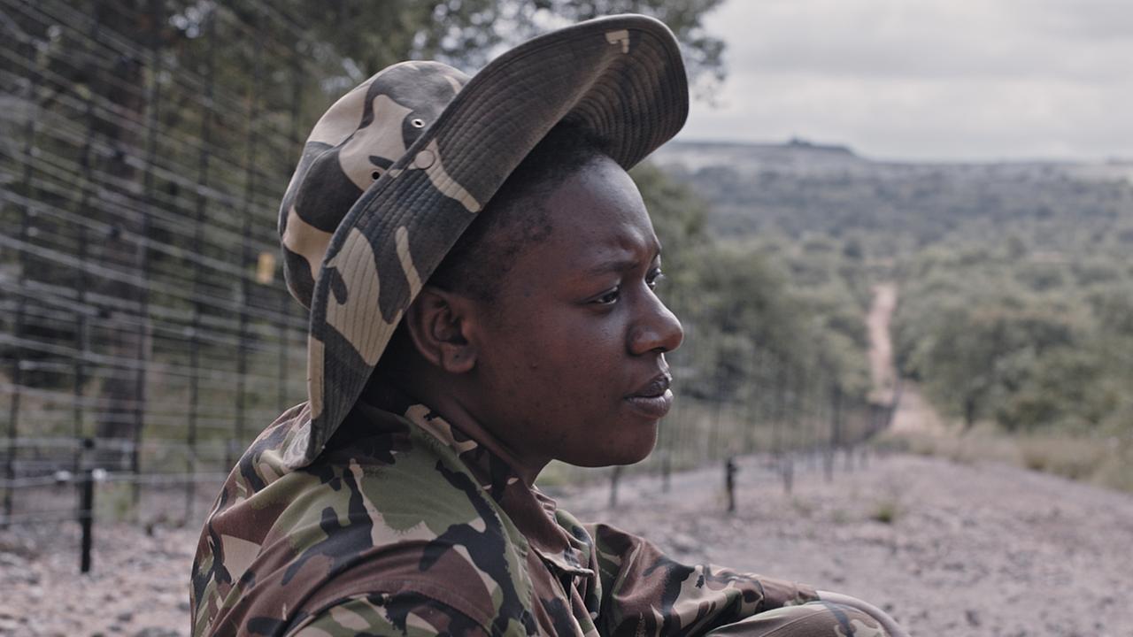 "Black Mambas": Die 30-jährige Rangerin Nkateko Mzimba. Sie trägt eine Rangeruniform und einen Hut in Tarnfarben. Im Hintergrund eine Waldlandschaft.