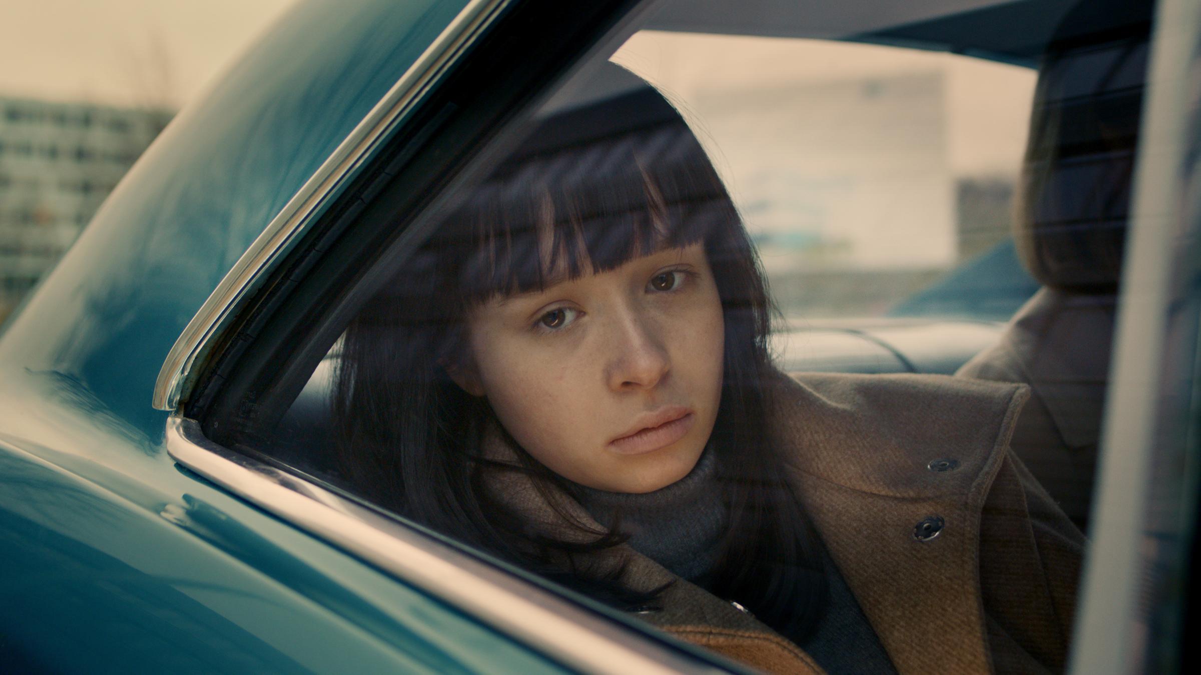 "THE ORDINARIES": Paula (Fine Sendel) sitzt auf der Rückbank eines Autos und schaut traurig aus dem Fenster.