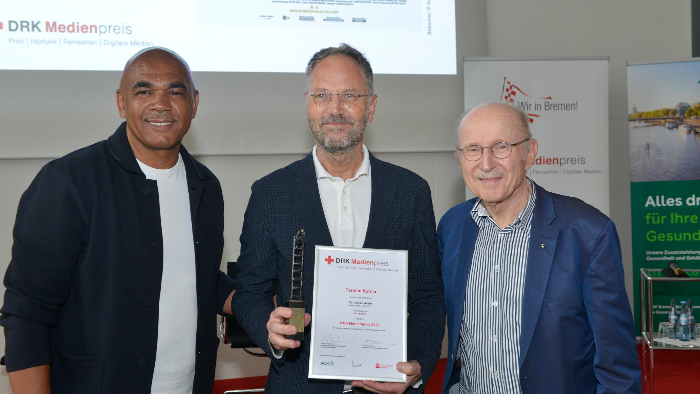 Verleihung des DRK-Medienpreise am 7.6.2022 inn Bremen. V.l.n.r.: Rigobert Gruber, Preisträger Torsten Körner ("Schwarze Adler"), Willi Lemke (Ex-Manager von Werder Bremen)