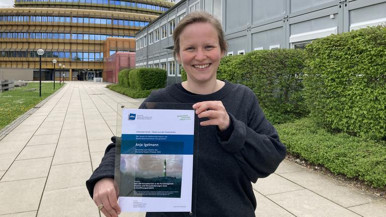 ZDF-Trainee Anja Igelmann steht vor dem Sendezentrum und präsentiert den diesjährigen Marianne-Englert-Preis des Vereins für Medieninformation und Mediendokumentation (vfm).