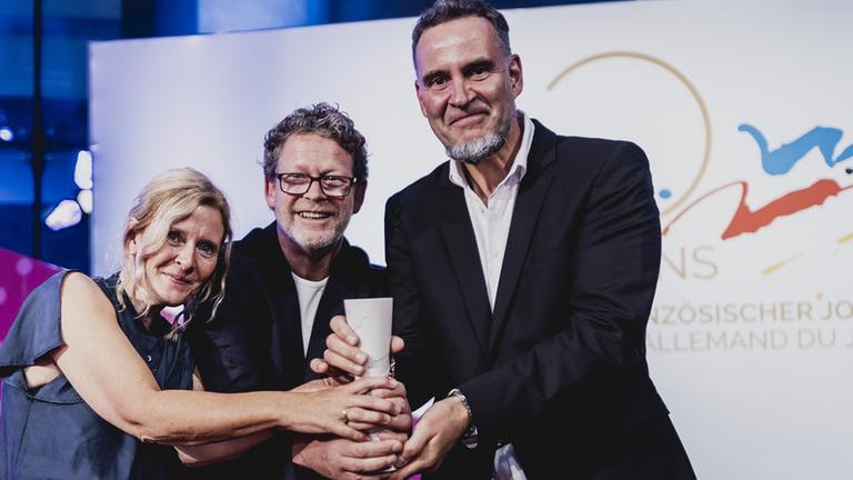 Deutsch-französischer Journalistenpreis 2023: Redakteurin Simone Müller, Filmemacher Jens Strohschnieder, Thorsten Eppert (Nordend Film) halten den Preis für "ZDFzoom: Weinen werden wir später" in der Hand