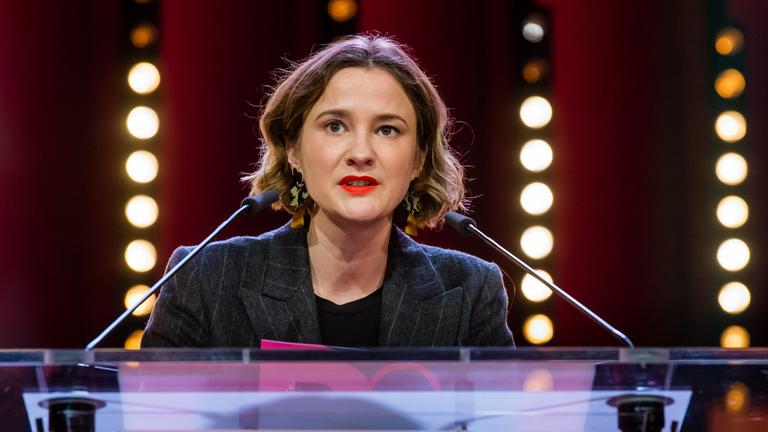 Porträtfoto der Regisseurin und Autorin von "Ivo", Eva Trobisch. Sie steht hinter einem Rednerpult, auf dem links und rechts je eion Mikrofon befestigt ist.