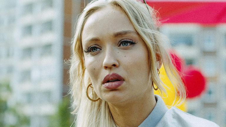 "Mels Block": Mel (Caro Cult) blickt in die Kamera. Im Hintergrund ein Wohnblock