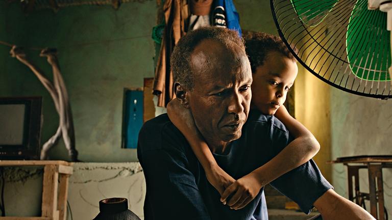 "The Village Next To Paradise (AT)": In einem abgelegenen Dorf in Somalia kämpft der alleinerziehende Vater Mamargade (Axmen Cali Faarax) mit den Herausforderungen des täglichen Lebens. Seinen Sohn Cigaal (Ahmed Mohamoud, r.) vergisst er manchmal in den Turbulenzen des Alltags.
