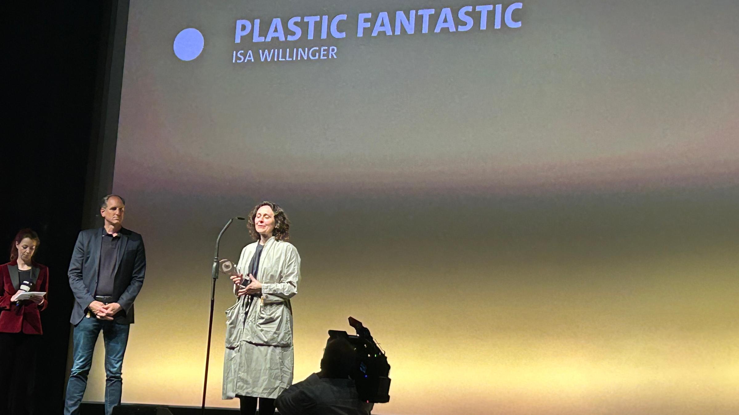 Verleihung Deutscher Dokumentarfilmpreis 21. Juni 2023 in Stuttgart: Verleihung des Publikumspreise für "Plastic Fantastic" an Isa Willinger. Sie steht auf der Bühne am Mikrofon und hält den Preis in den Händen.