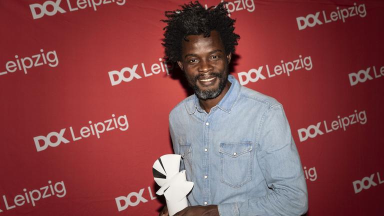 Preisverleihung "Silberne Taube" beim 67. DOK Fest Leipzig (3.11.2024): Preisträger Pierre Michel Jean mit der Preistrophäe
