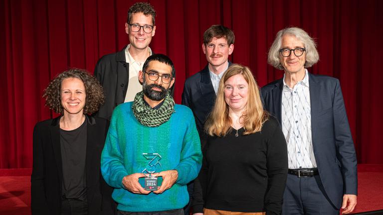 Vergabe 3sat-Dokumentarfilmpreis auf der 48. Duisburger Filmwoche (9. November 2024): Preisträger Faraz Fesharaki (Mitte) mit der 3sat-Jury Laura Coppens (links), Sebastian Höglinger (zweiter von links) und Britt Beyer (zweite von rechts). Rechts im Bild: Johannes Dicke, Planungschef von 3sat. Dritter von rechts: Festivalleiter Alexander Scholz.