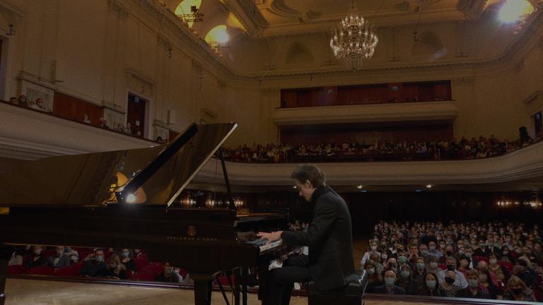 "Pianoforte - Der Chopin-Wettbewerb in Warschau": Der Pianist Marcin Wieczorek aus Polen sitzt auf der Bühne eines Konzertsaals an einem Flügel. Im Hintergrund ist das Saalpublikum zu sehen