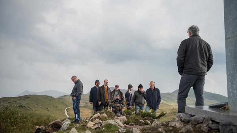 "Men don't cry / Männer weinen nicht": Acht ehemlige Soldaten habenn sich auf einem Berggipfel versammelt. Im Vordergrund rechts steht ihr Therapeut Ivan (Sebastian Cavazza) mit dden Rücken zur Kamera.