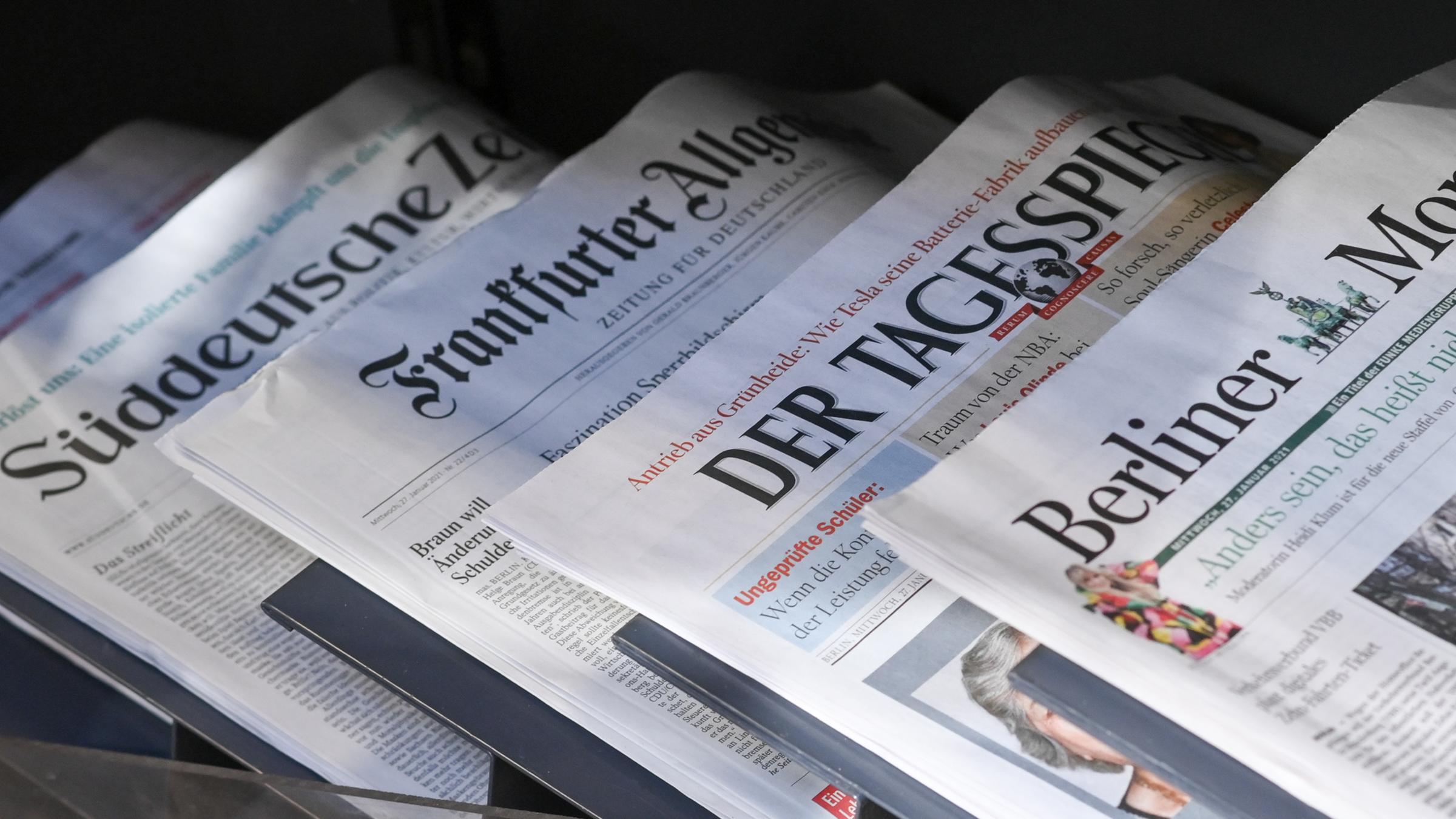 Zeitungen liegen in einer Auslage in einem Zeitschriftenladen.