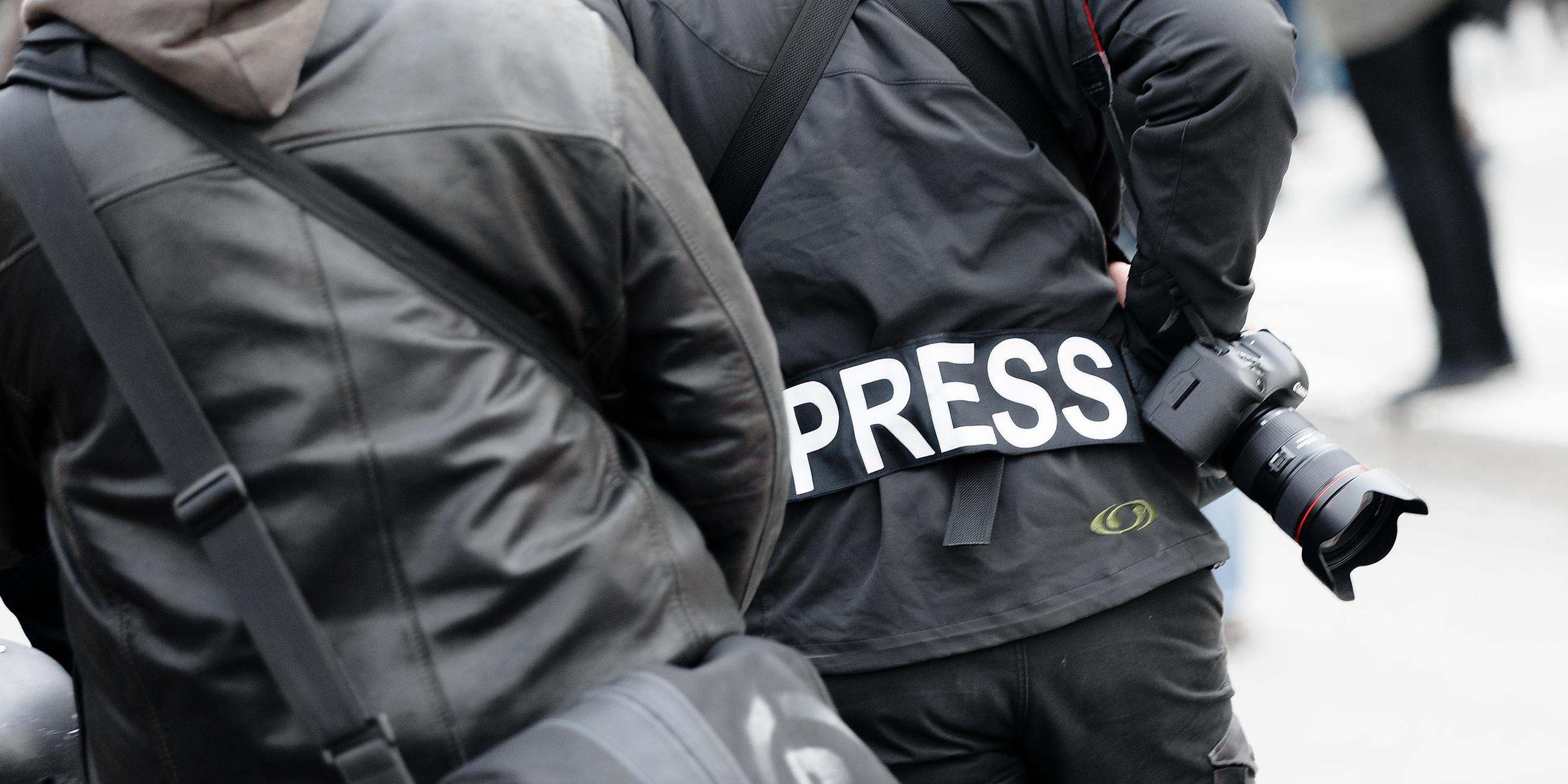 Ein Fotoreporter trägt bei einer Demonstration einen Aufnäher auf seiner Jacke mit dem Wort "PRESS". (Archiv)