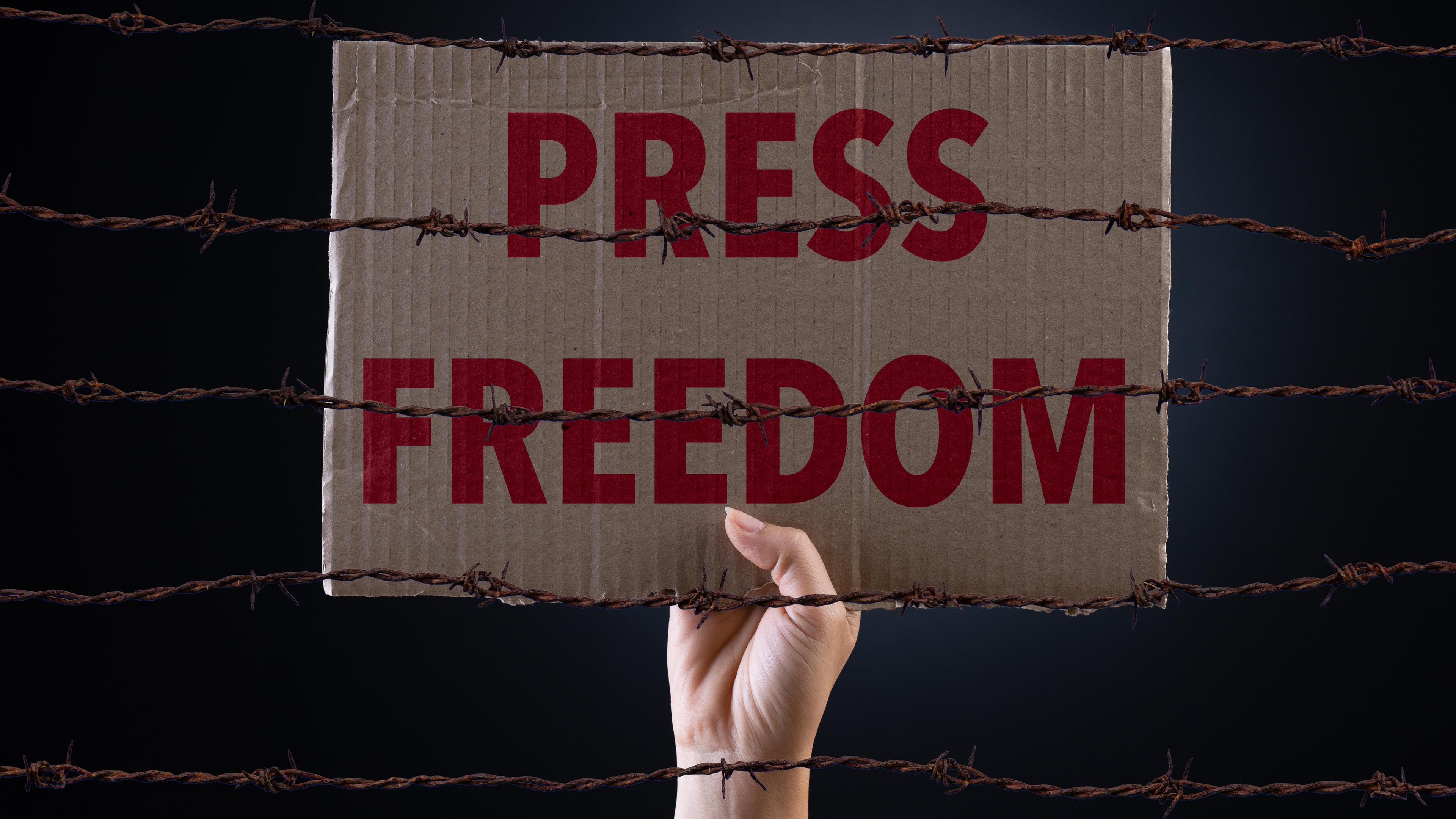 Ein Schild "Press Freedom", was hinter Stacheldraht hochgehalten wird.