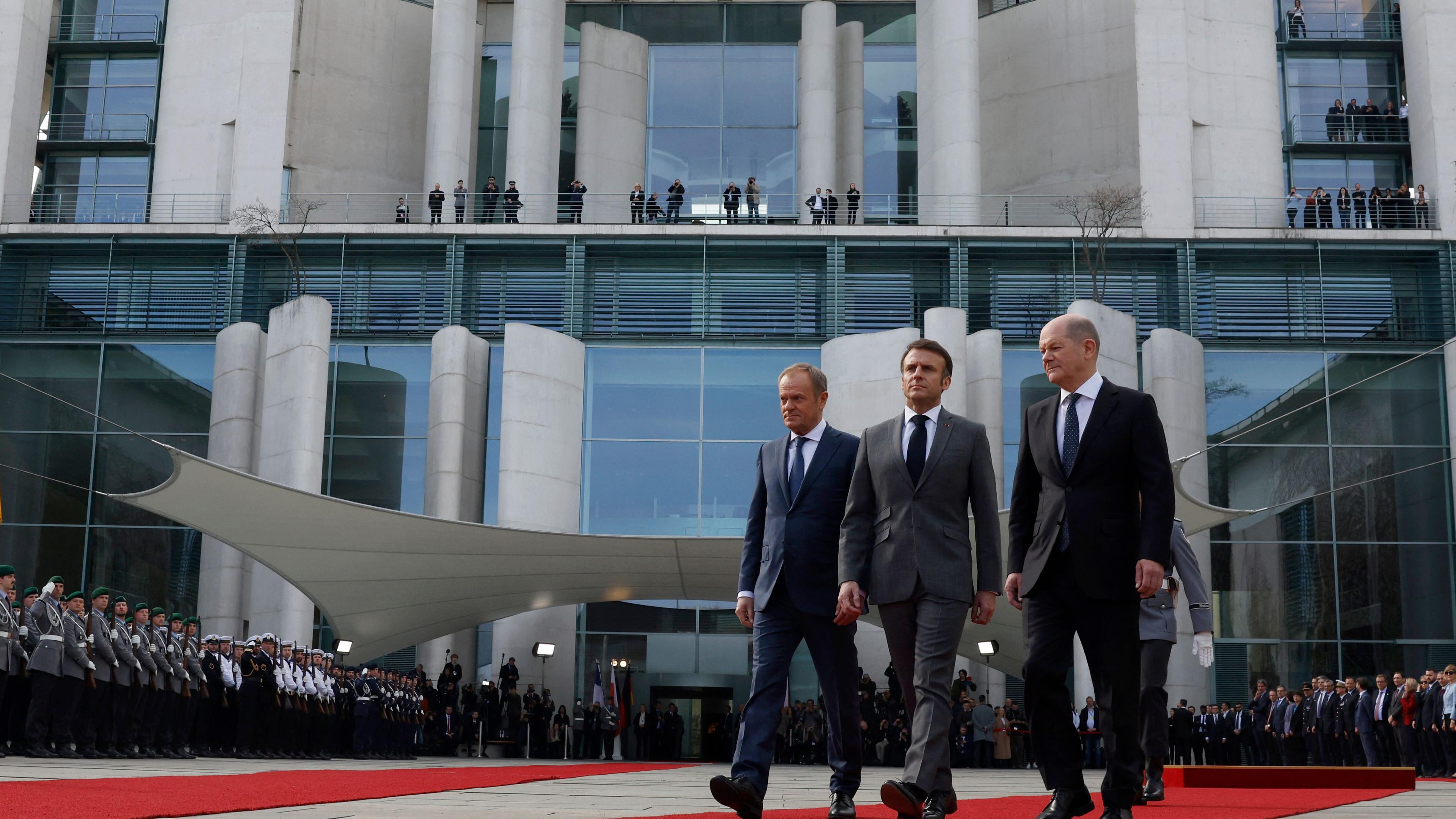 Der deutsche Bundeskanzler Olaf Scholz (R), der polnische Premierminister Donald Tusk (L) und der französische Präsident Emmanuel Macron schreiten über einen roten Teppich