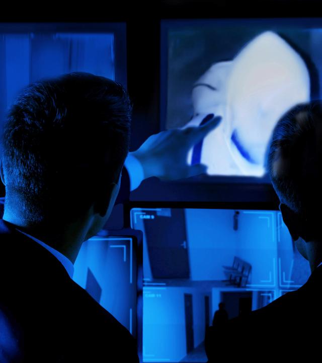 Sicherheitsdienst betrachtet Aufnahmen von Überwachungskameras