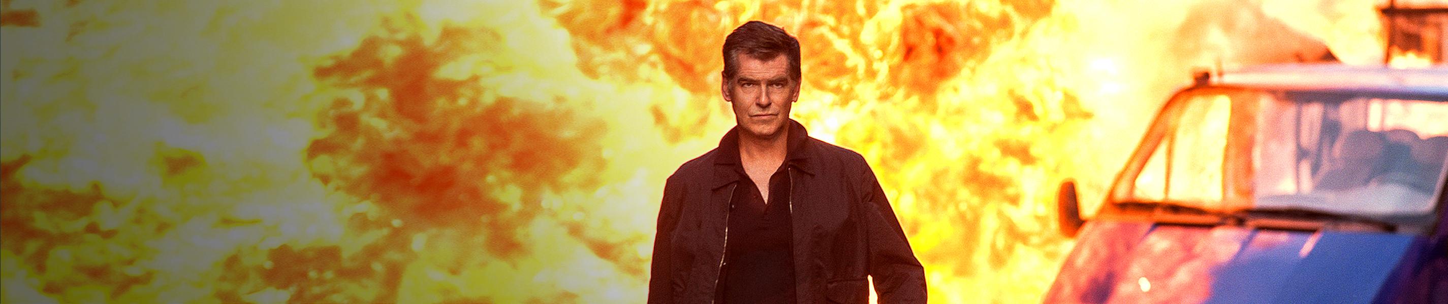 Peter Devereaux (Pierce Brosnan) läuft lässig eine Straße entlang. Hinter ihm sieht man eine riesige Explosion.