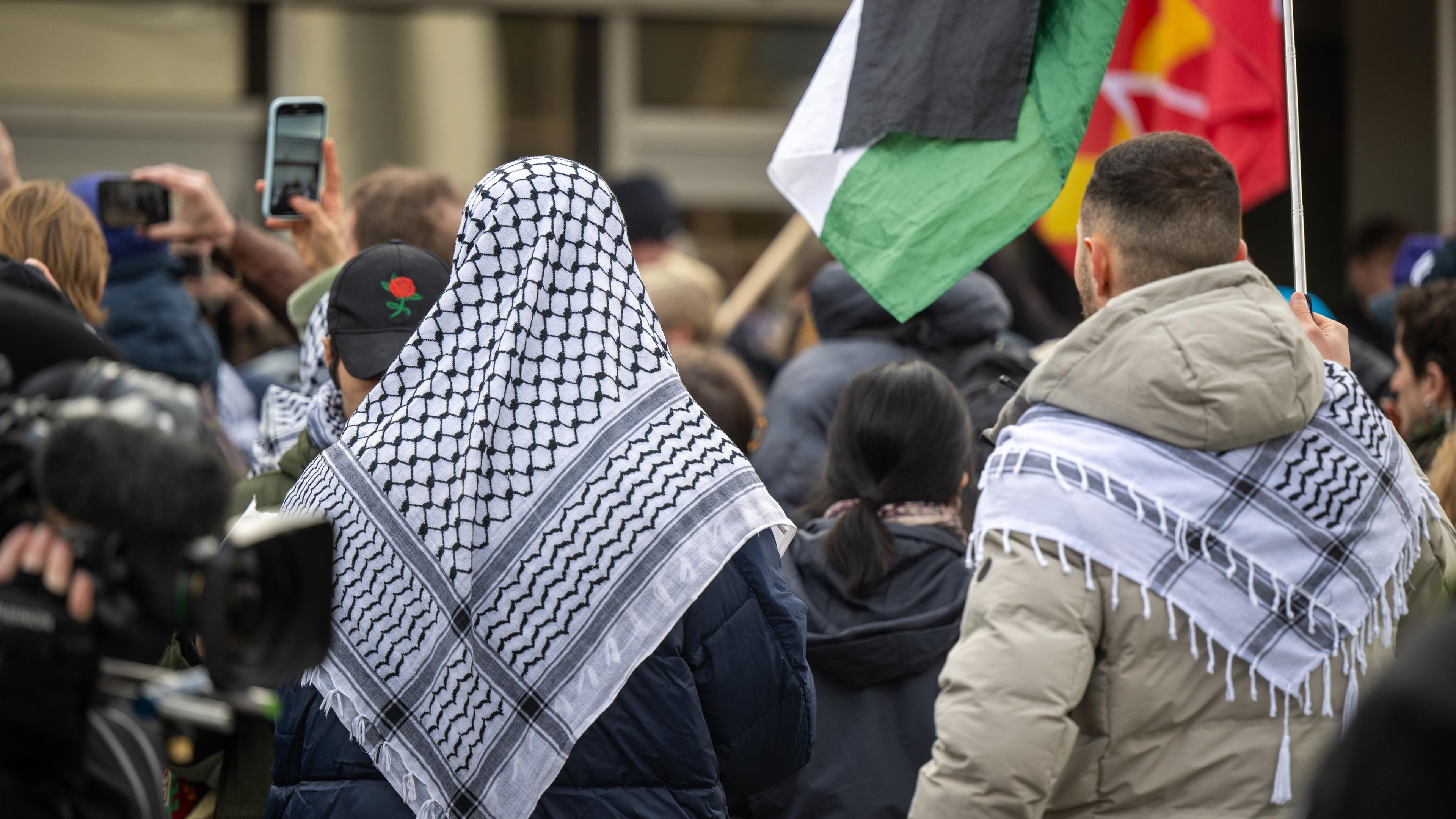 Berlin: Teilnehmer der propalästinensischen Kundgebung unter dem Motto "Solidarität mit Palästina" stehen mit Palästinenser-Tüchern und Flaggen vor der Mensa II an der Freien Universität (FU).