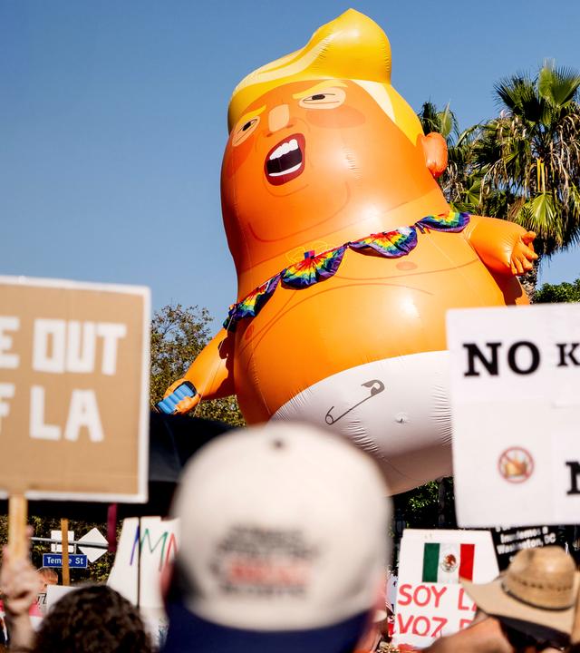 Demonstration gegen Trump in L.A., in der Mitte ein aufgeblasener Ballon mit Trump in Windeln - Motiv. Rechts vorne eine Schild mit der Aufschrift „No