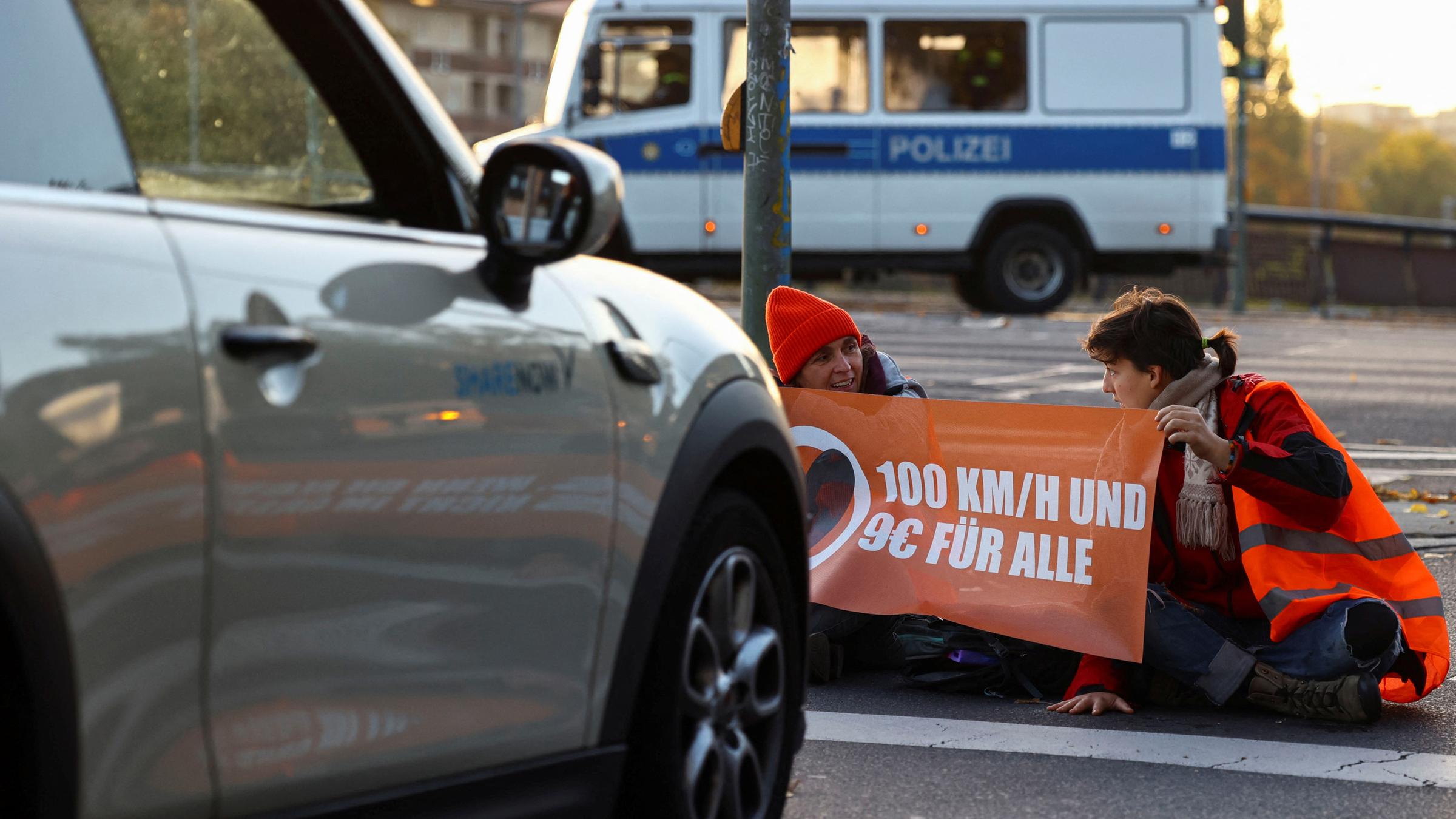 Archiv: Aktivisten der "Letzten Generation" protestieren am 11. 10. 2022 an der Ausfahrt einer Autobahn in Berlin für eine Geschwindigkeitsbegrenzung auf Autobahnen sowie für erschwingliche öffentliche Verkehrsmittel.