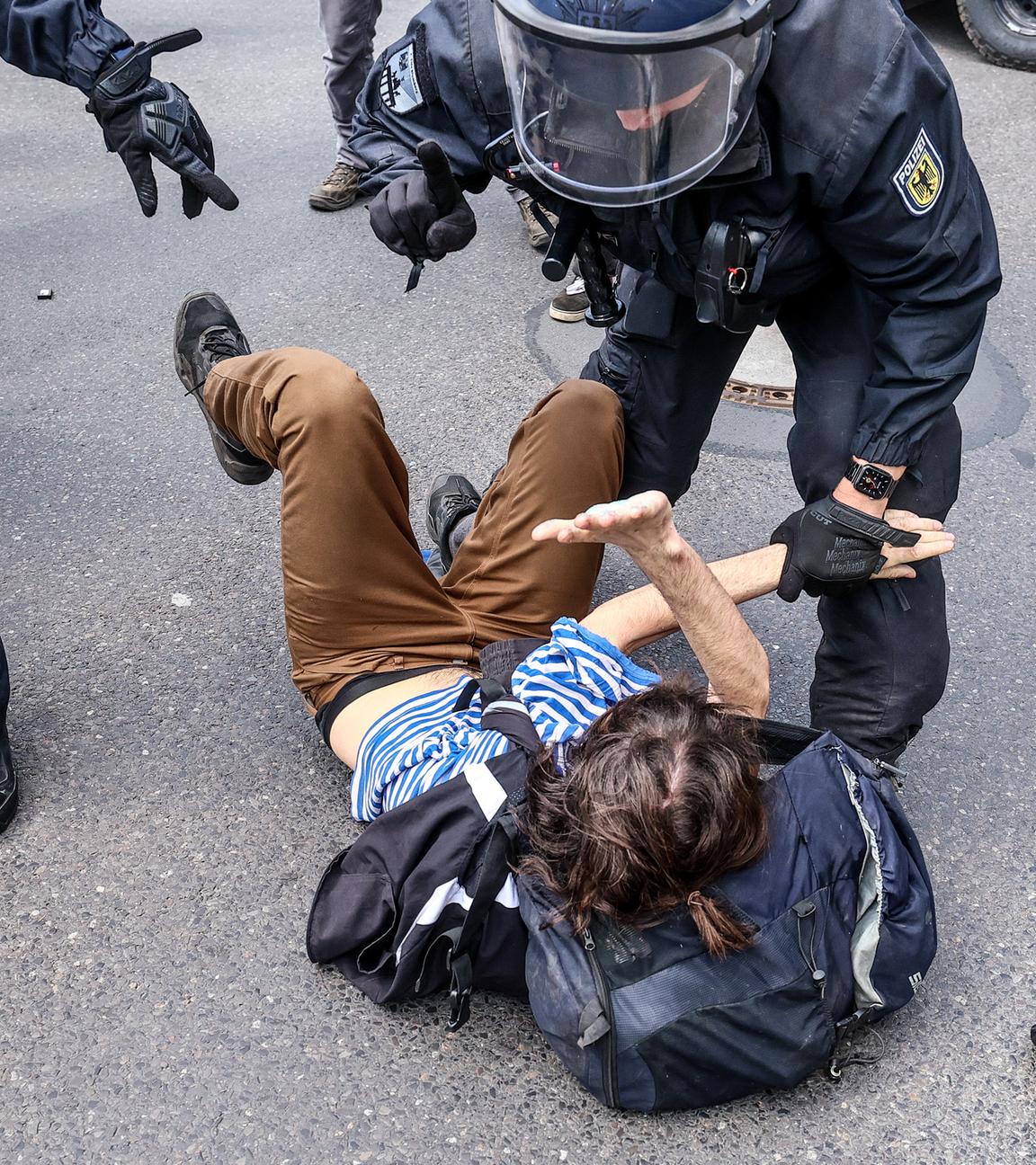 Polizisten diskutieren mit einem am Boden liegenden Demonstranten.