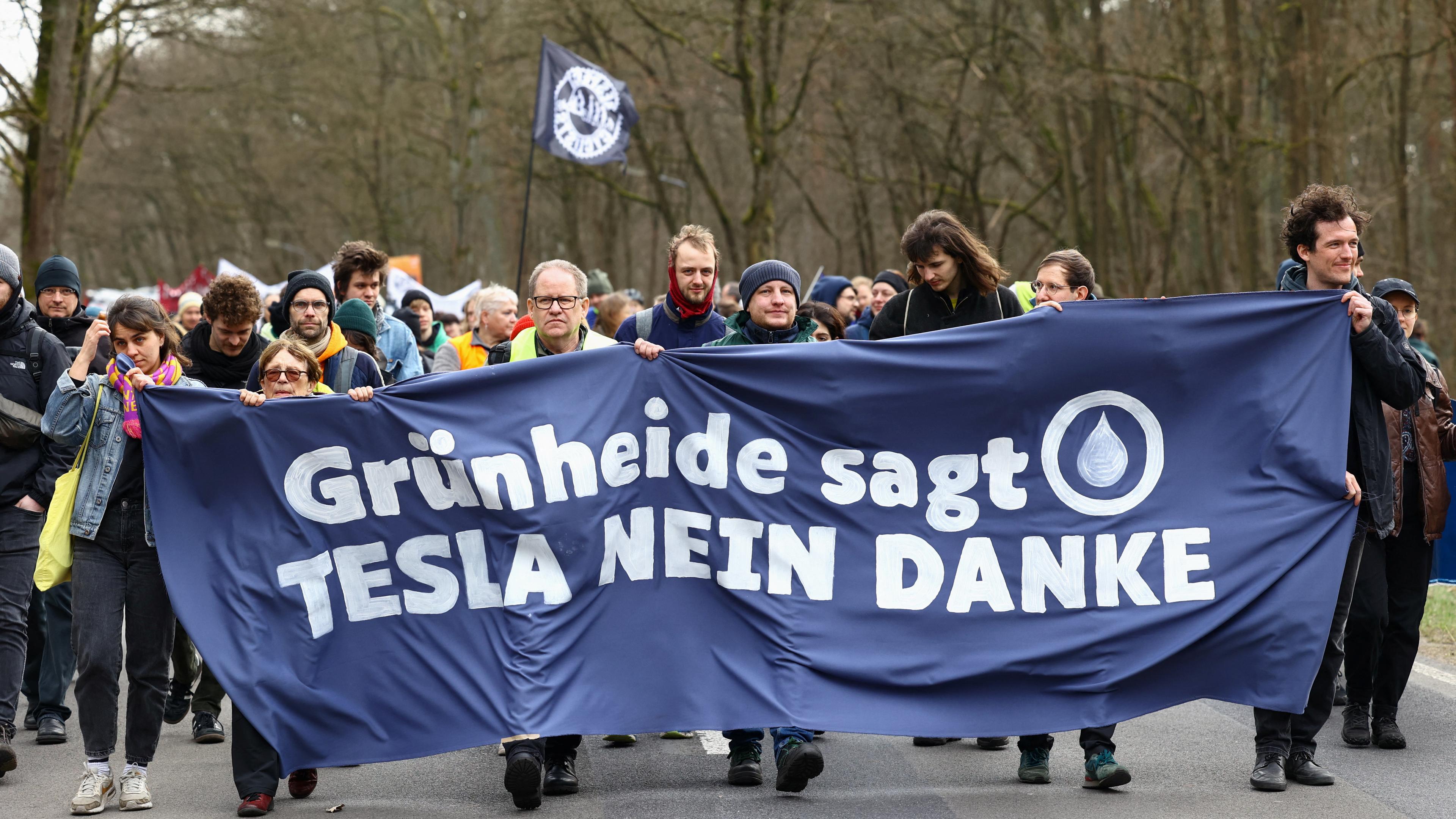 10.03.2024: Umweltaktivisten halten ein Transparent während eines Protestes gegen den Ausbau der sogenannten Tesla Gigafactory in Grünheide bei Berlin. Auf dem Transparent steht: "Grünheide sagt Tesla nein danke".
