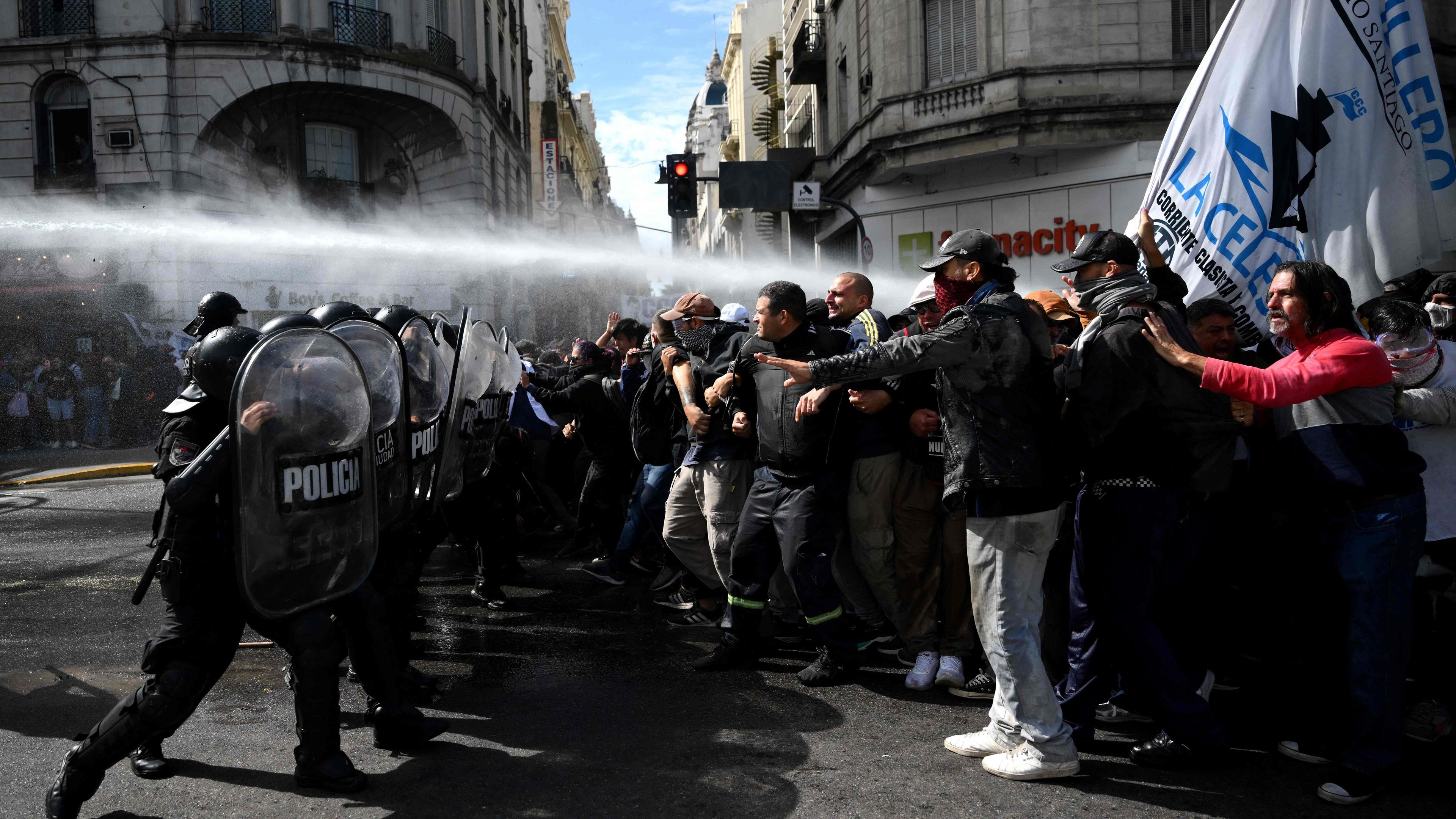 Demonstranten stehen Polizisten gegenüber. Zudem ist ein Wasserwerfer im Einsatz.