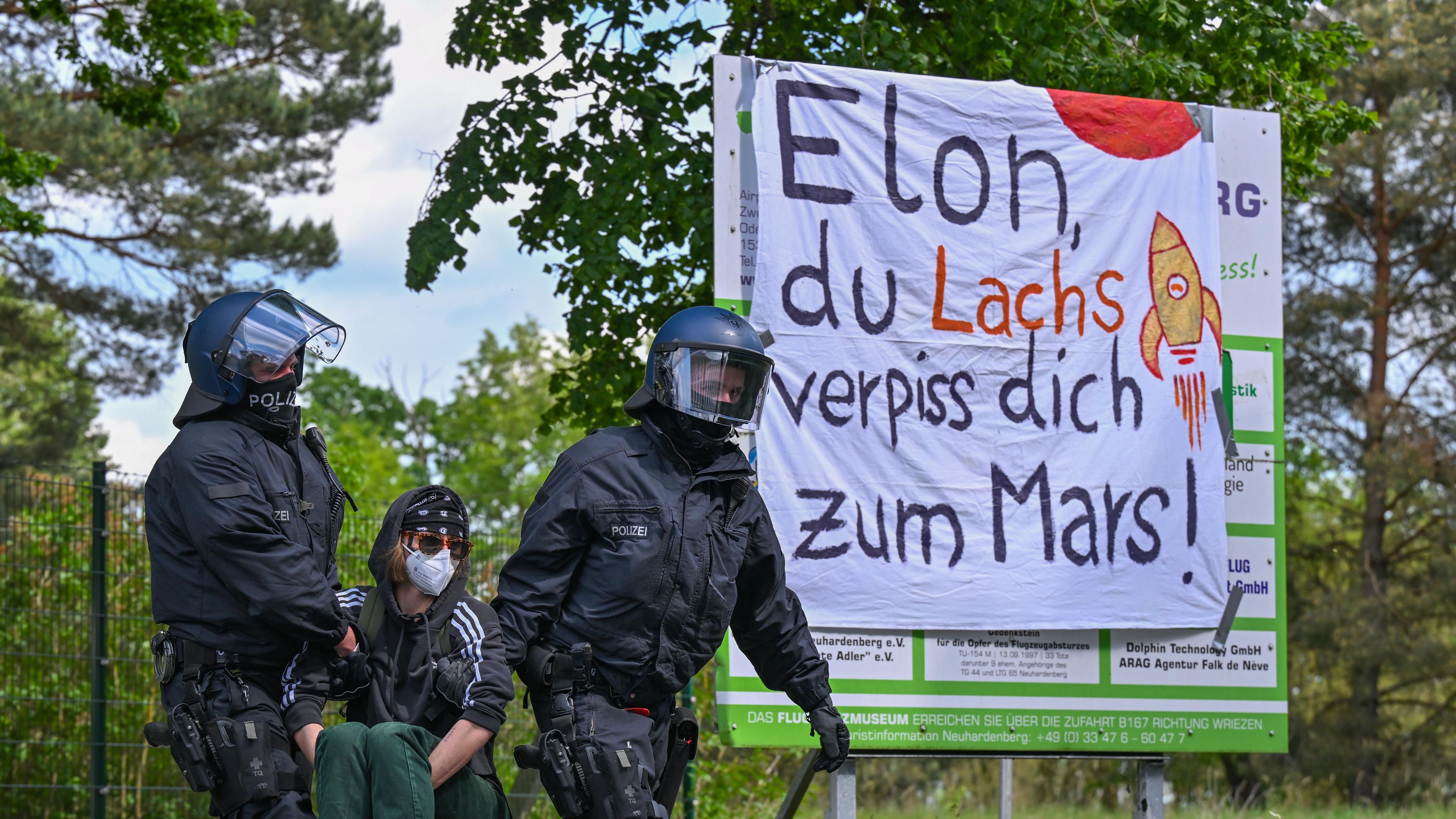 Polizisten tragen einen Aktivisten von der Zufahrt zum Flugplatz Neuhardenberg weg. 