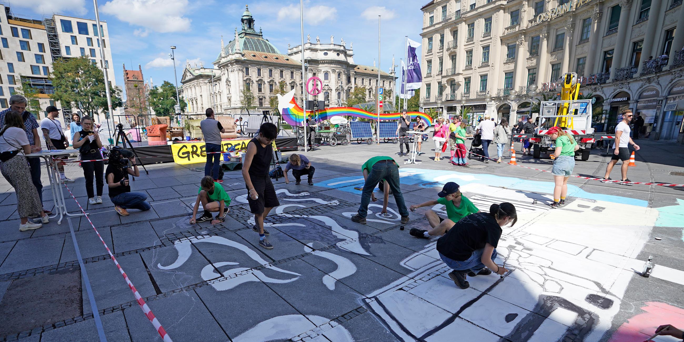Mitglieder verschiedener Umweltschutzorganisationen bemalen am Rande einer öffentlichen Podiumdiskussion den Boden am Karlsplatz. (02.09.2023)