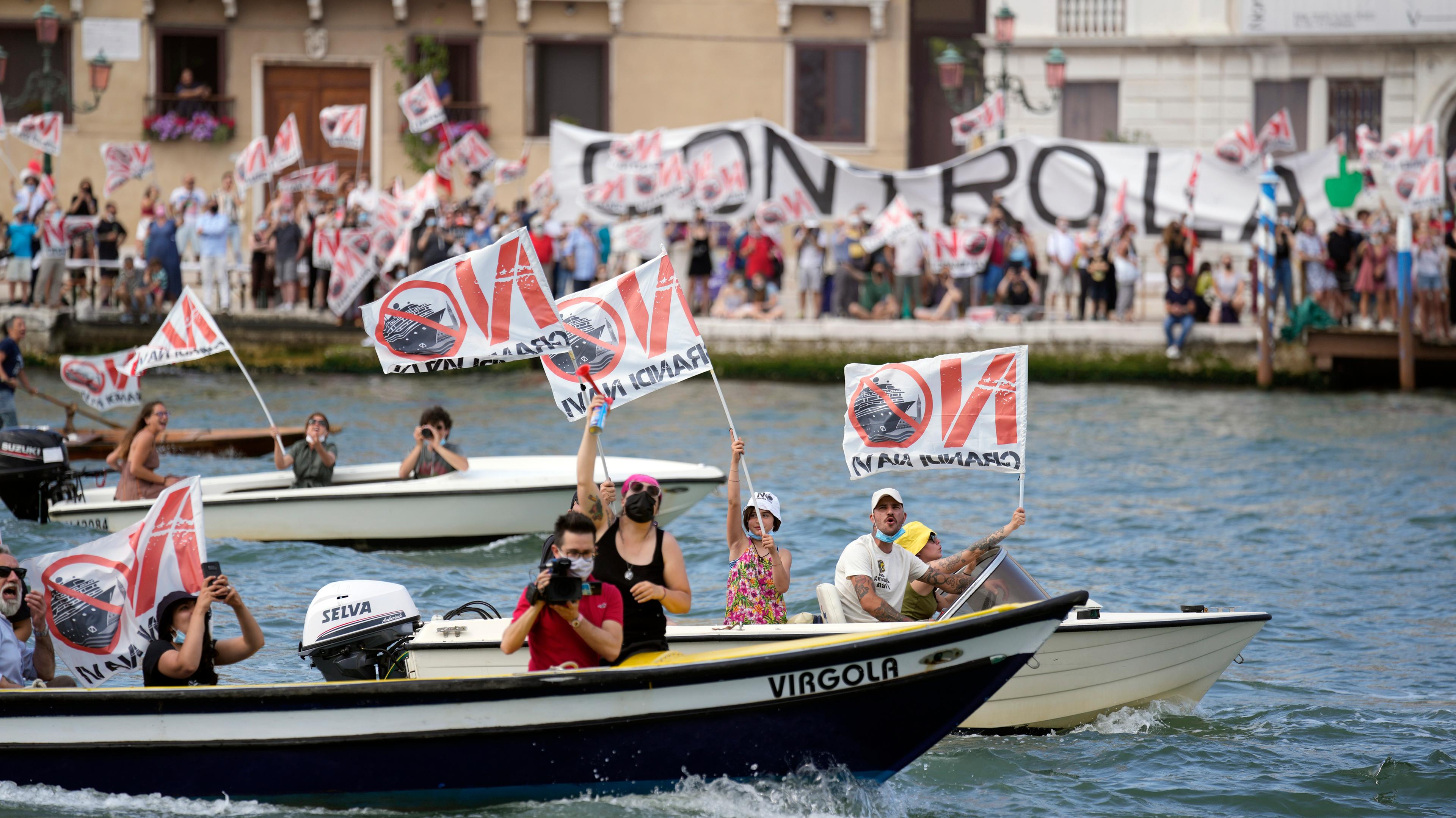 Menschen am Ufer und auf Booten protestieren mit Bannern und Fahnen