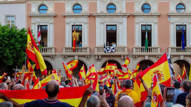 Menschen demonstrieren in Spanien mit ihrer Nationalflagge gegen die Migrationspolitik der Regierung.