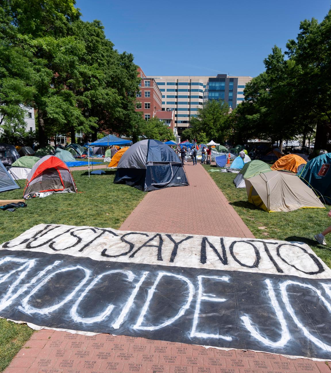 Im Innenhof einer Uni stehen mehrere Zelte auf einem Weg liegt ein Banner mit der Aufschrift "Sag Nein zu Völkermord Joe"