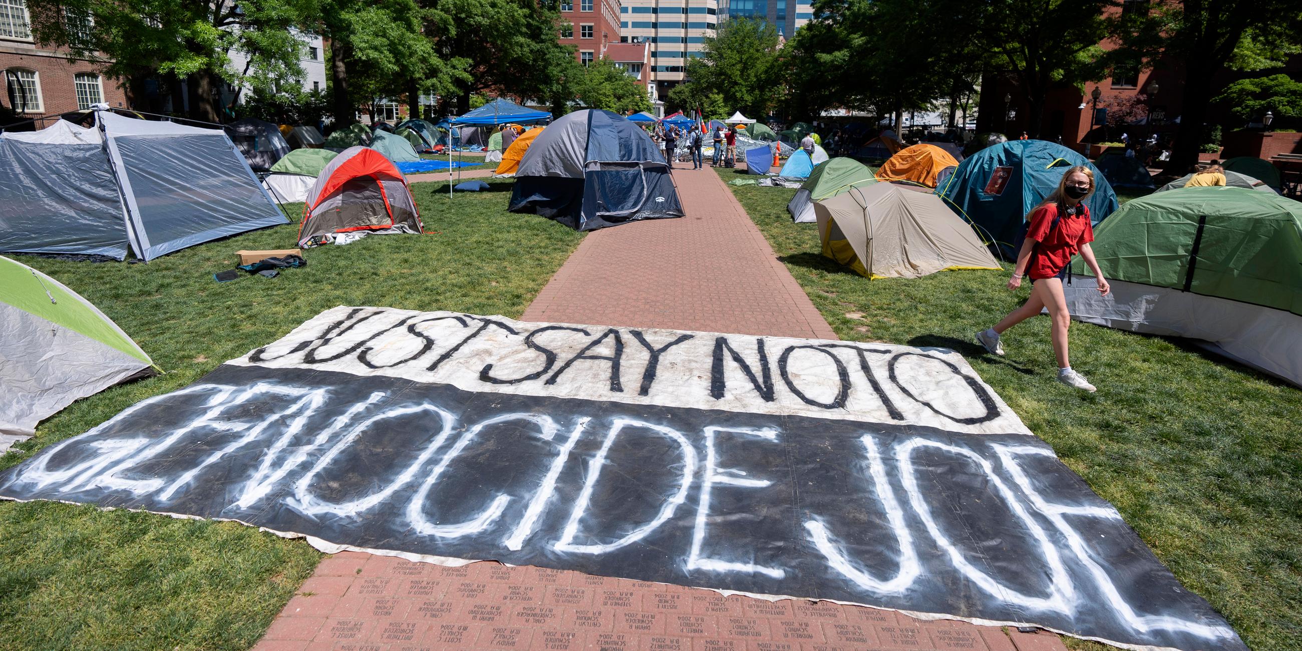 Im Innenhof einer Uni stehen mehrere Zelte auf einem Weg liegt ein Banner mit der Aufschrift "Sag Nein zu Völkermord Joe"